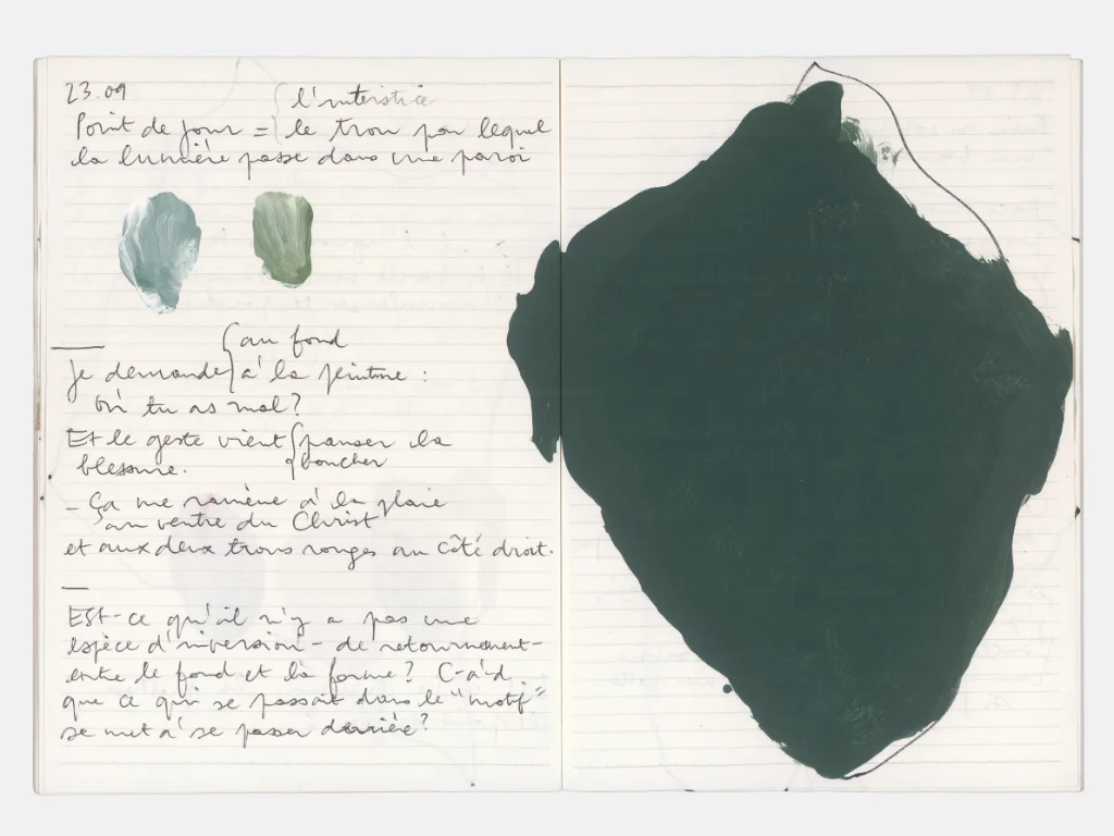 Page de carnet d'atelier de Claire Colin-Collin : fond de page blanche à lignes bleutées, avec des notes manuscrites à l'encre noire et des taches d'aquarelle verte et bleu-gris. À gauche, un texte daté du 23.09 évoque des réflexions sur l'intérêt, la lumière traversant une paroi, et des questions sur la forme et le fond. À droite, une grande forme organique noire, évoquant une silhouette ou une ombre, occupe la majeure partie de l'espace. Deux petites taches de couleur (bleu-gris et vert pâle) sont visibles près du texte.